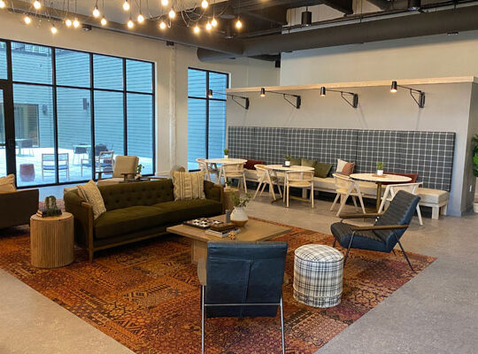 Modern interior space featuring custom woodworking, a green sofa, and wooden tables, designed for comfort and collaboration, reflecting Schlaegle Design Build Associates' craftsmanship and innovative design solutions.