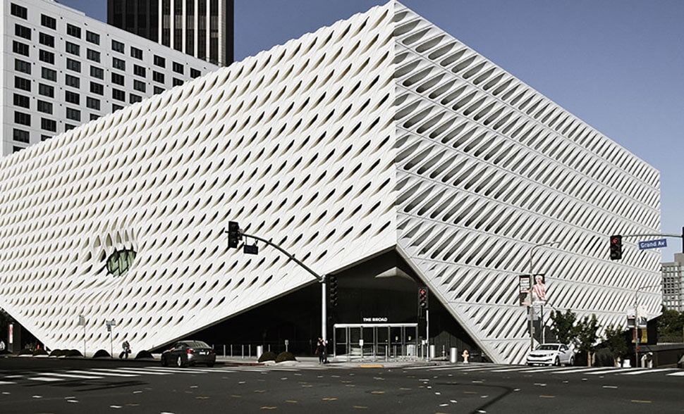 Architectural image of a modern educational building with a distinctive white fa&ccedil;ade featuring diamond-shaped patterns, located at a street intersection with signage and vehicles in view, representing Schlaegle Design Build Associates' portfolio in educational architecture.