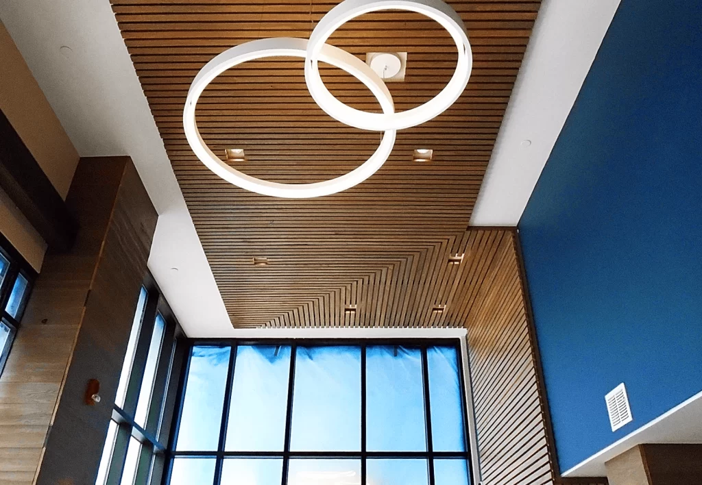 Modern ceiling design featuring circular light fixtures and wood paneling, showcasing architectural elements relevant to educational building projects by Schlaegle Design Build Associates, Inc.